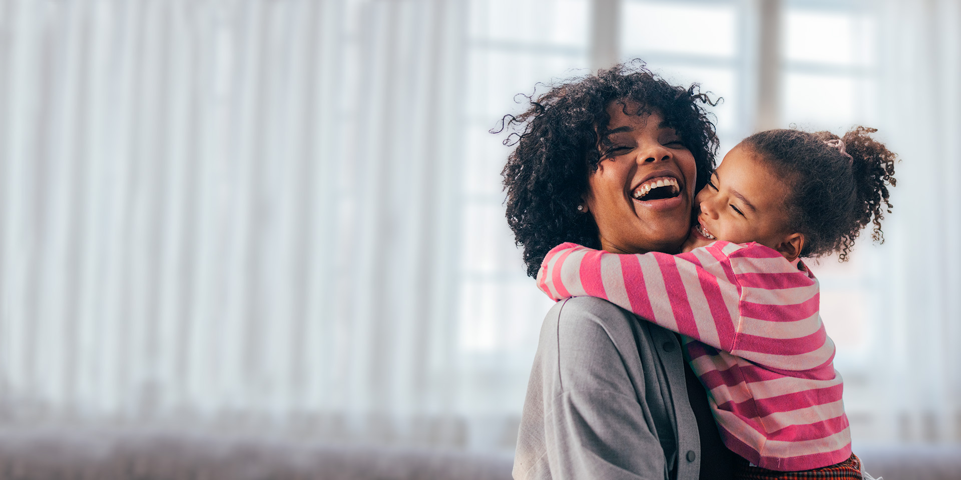 mom and daughter hugging in front of window