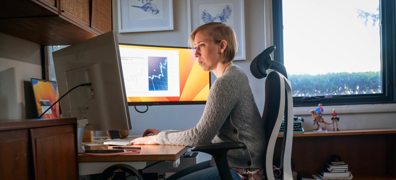 A T. Rowe Price employee works remotely from home at her computer while wearing a headset.