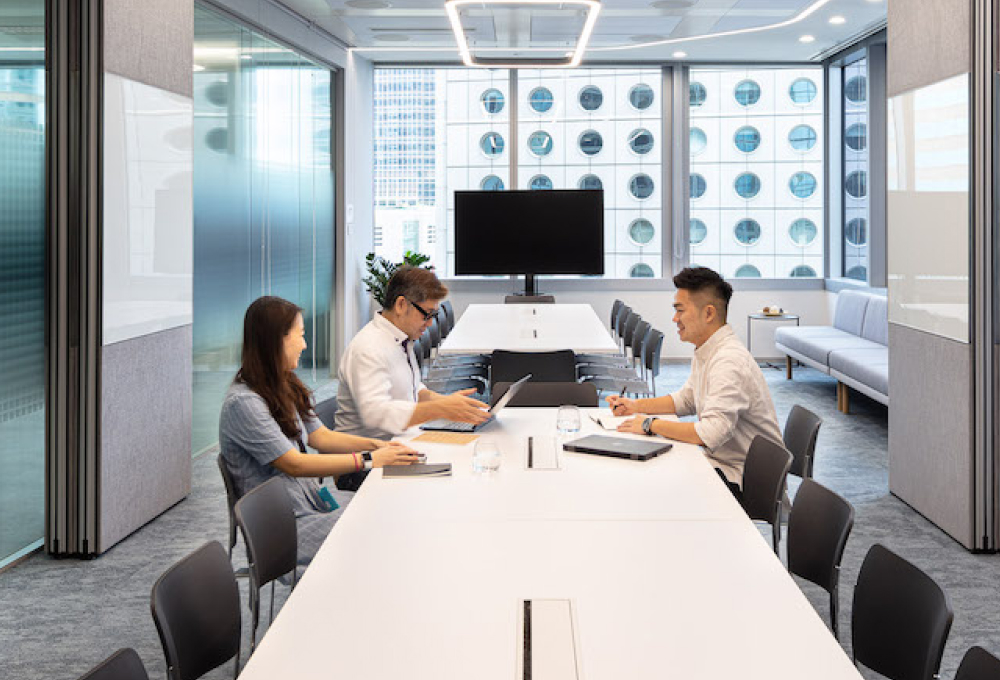 Three people sitting at a table in an office