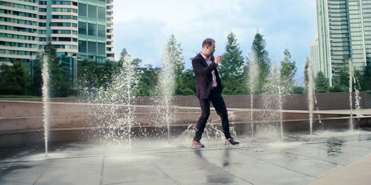 Man dressed in a suit dancing in a fountain.